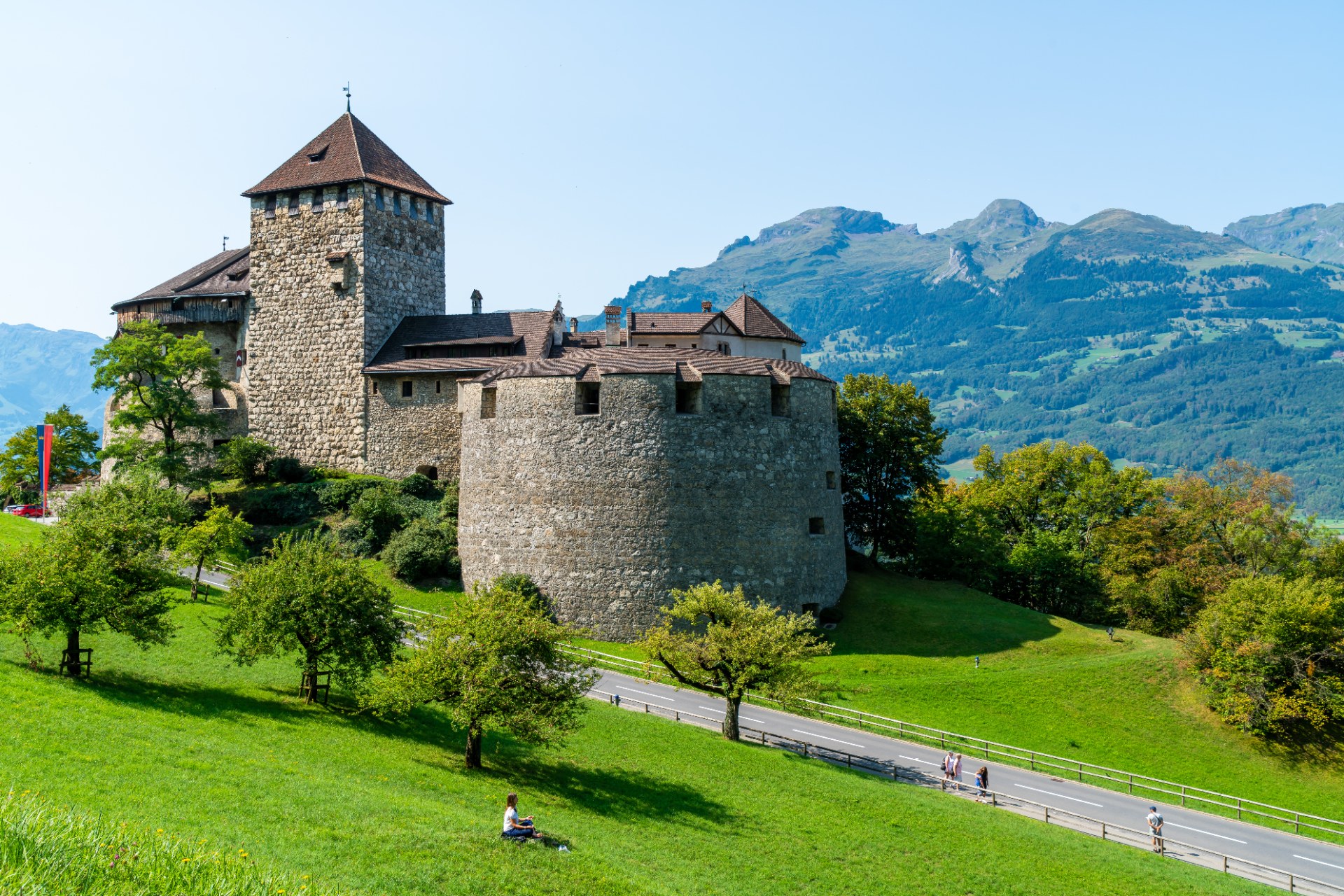 Hrad Vaduz na zelenom svahu na pozadí hôr v Lichtenštajnsku
