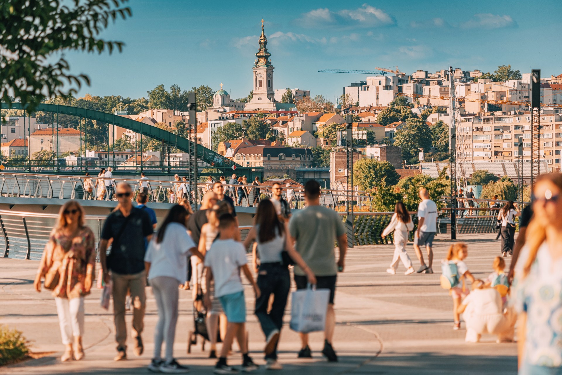 Ľudia sa prechádzajú po nábreží Sávy v Belehrade, v pozadí staré mesto a kostolná veža